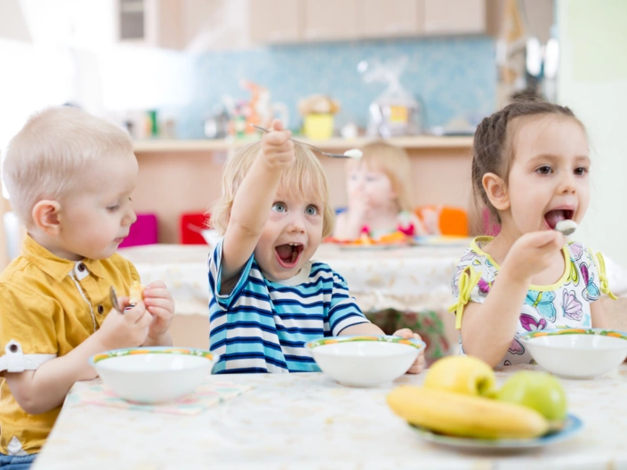 Drei Kindergartenkinder essen Grießbrei.