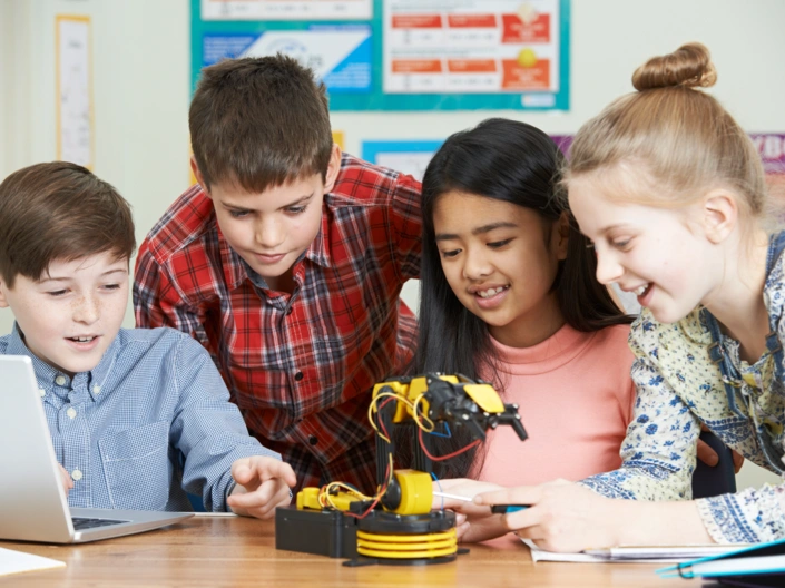 Schülerinnen tüfteln gemeinsam an einem kleinen Roboterarm.