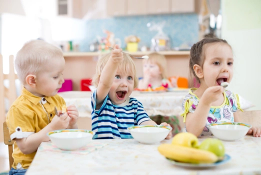 Drei Kindergartenkinder essen Grießbrei.