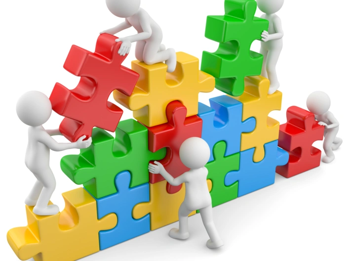 Kleine Figuren setzen gemeinsam eine Wand aus Puzzleteilen zusammen.