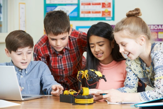 Schülerinnen tüfteln gemeinsam an einem kleinen Roboterarm.